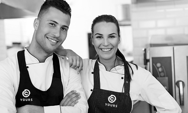 Zwei Gastronomiekollegen lächeln in die Kamera
